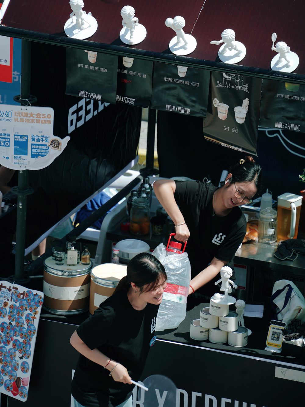 UNDER x PERFUME market stand serving drinks beside the figurine display